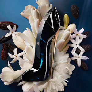 Carolina Herrera Good Girl kvepalai tarp gėlių tamsiame fone – Aromatale.lt